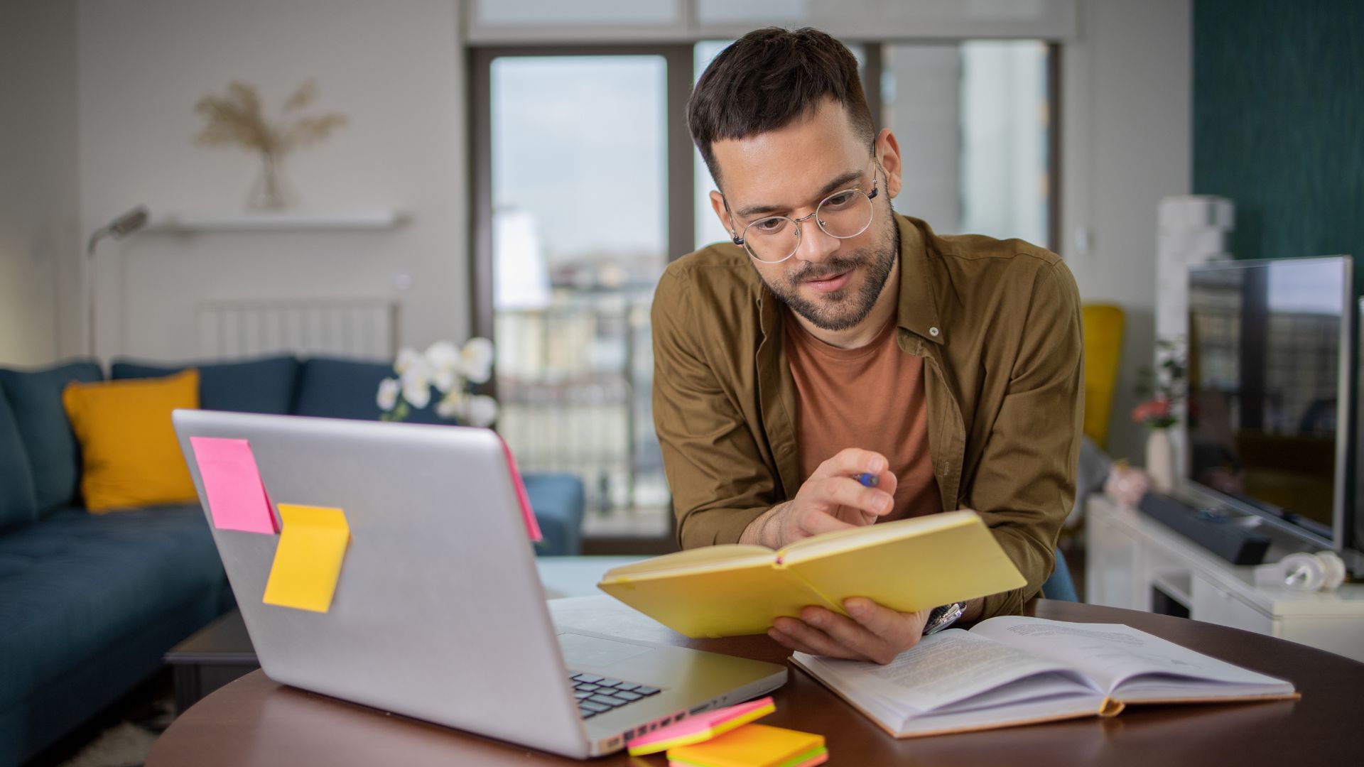 Homem adulto estudando curso técnico EAD da SedeEdu pelo notebook, com livros e anotações em casa