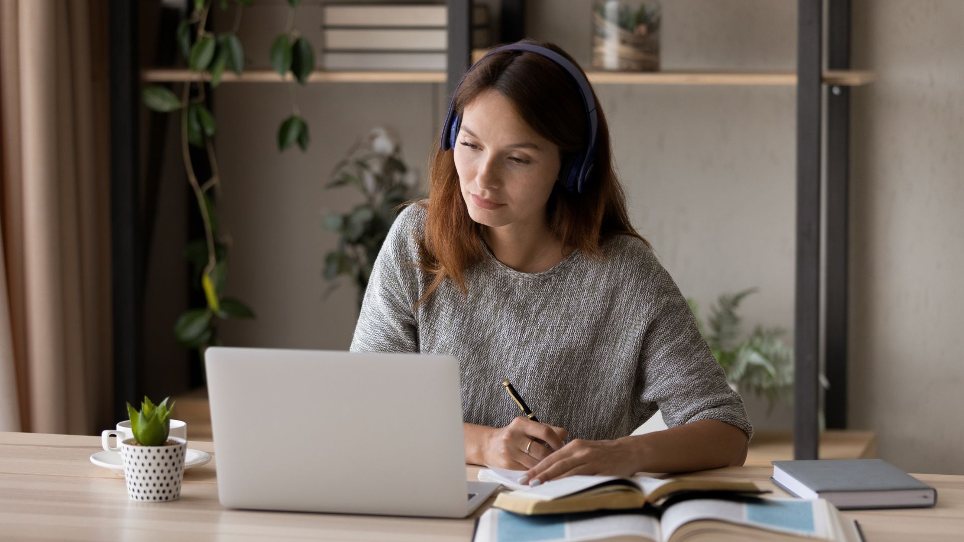 Adulta de 35 anos estudando curso EAD da SedeEdu pelo notebook, com fones de ouvido, em casa